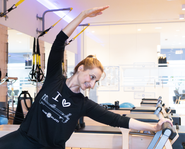 Instrutora de pilates num exercício em cima do reformer no Clu